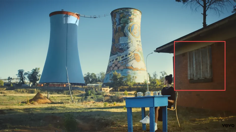 Jain sitting on a wall on Ohm Crescent in Soweto looking towards Orlando Power Station in Makeba music video at 1:00